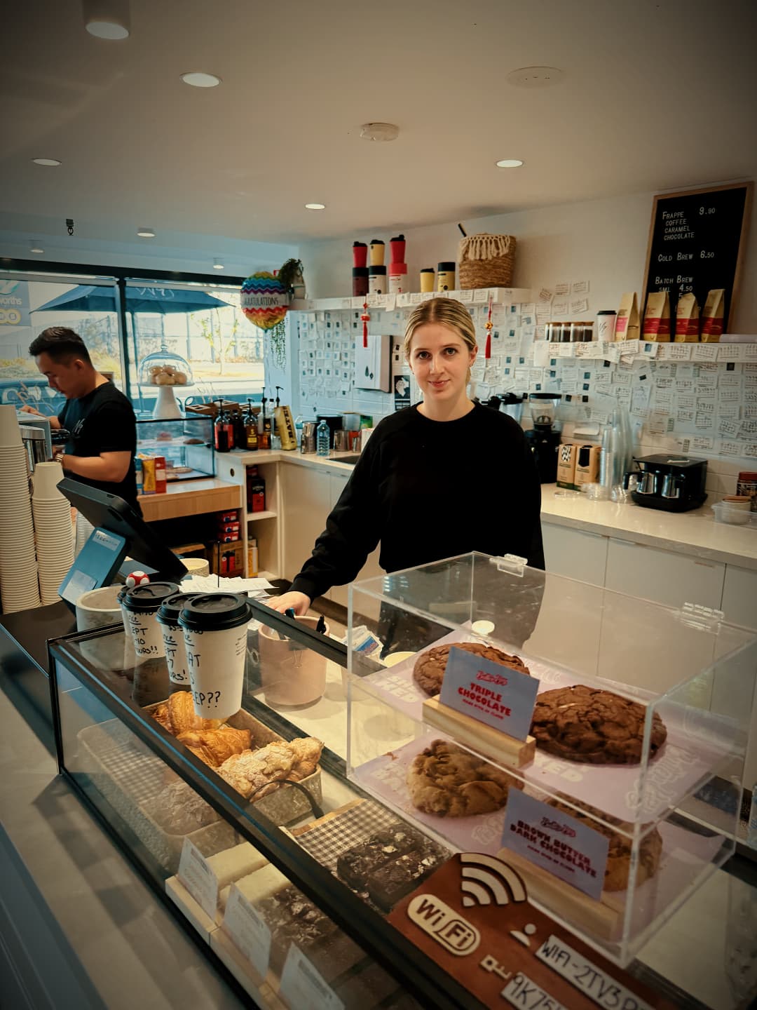 Friendly staff member serving customers behind the counter at No9 The Cafe.
