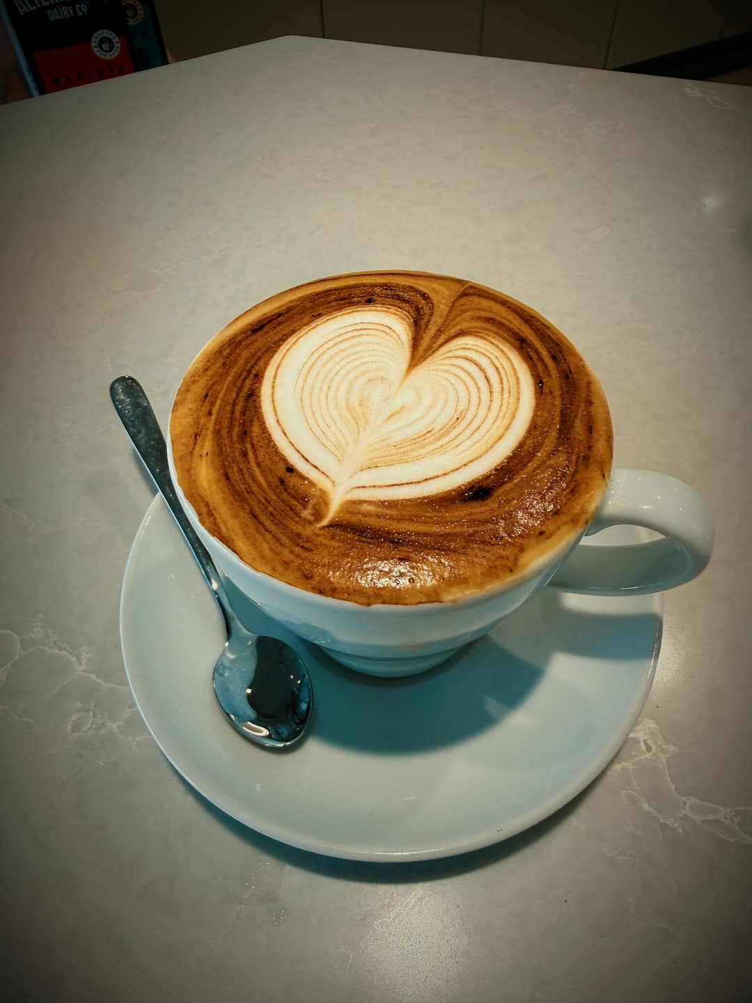 Barista-made coffee with heart latte art in a white cup and saucer at No9 The Cafe.